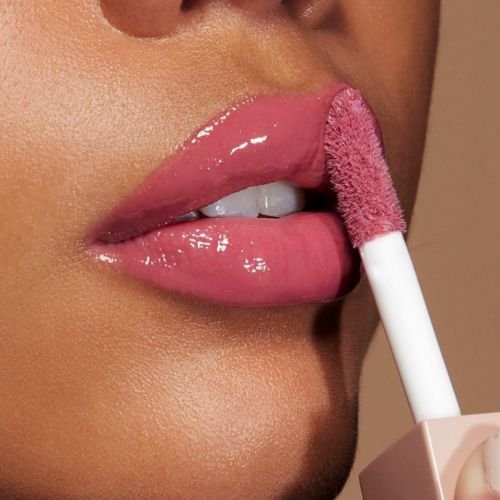 Mulher a aplicar um gloss rosa da maybelline 